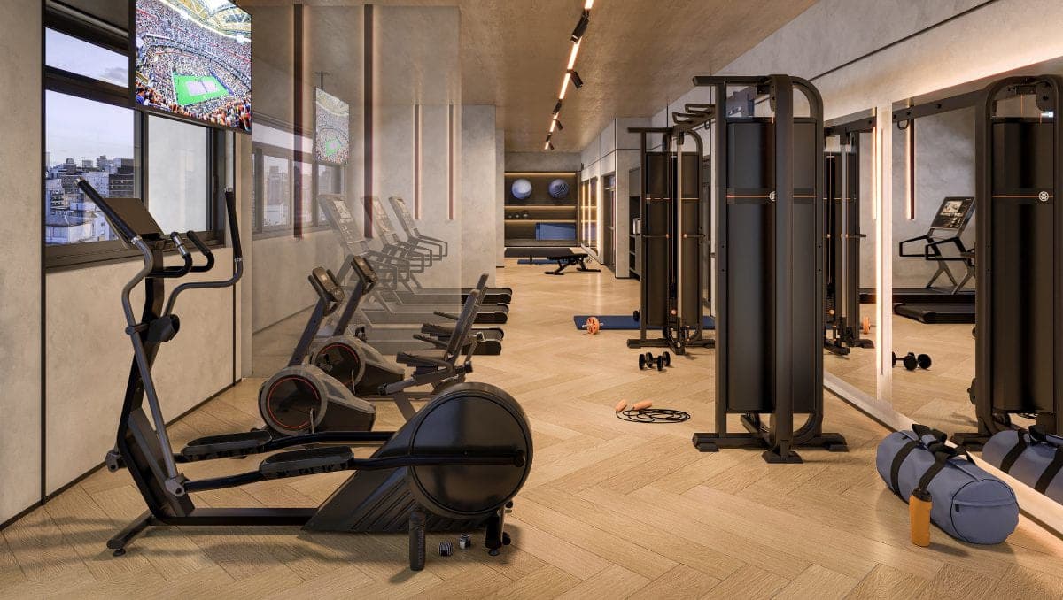 Academia com elípticos, esteiras, estações de musculação, espelho e TV, com janela para a cidade